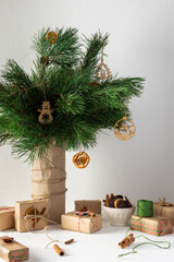 Festive Christmas table, vase with pine branches and toys, gift boxes and a plate of chocolate cookies, dried citrus fruits, cinnamon with star anise