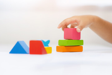Close up Children hand Practice the skills of playing with wooden toys on the table in living room. Asian little boy education from home. Developing children's learning before entering kindergarten