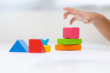 Close up Children hand Practice the skills of playing with wooden toys on the table in living room. Asian little boy education from home. Developing children's learning before entering kindergarten