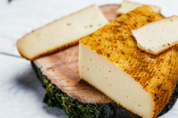 Cheese pieces of hard yellow Dutch gouda cheese with dried spices on wooden board