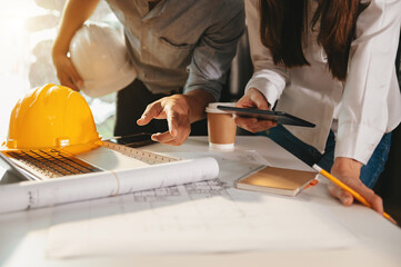 Creative architect projecting on the big drawings in the dark loft office or cafe in morning light..