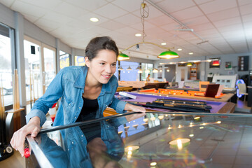 young woman playing on the pinball machine in game room - Powered by Adobe
