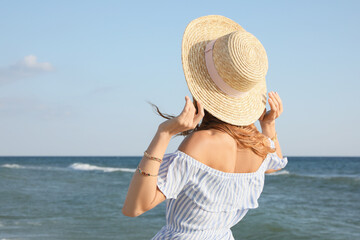 Woman with straw hat near sea on sunny day