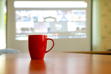 Red coffee cup on wooden in blurred conference room background