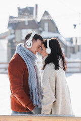 side view of smiling couple hugging while listening music in headphones outside