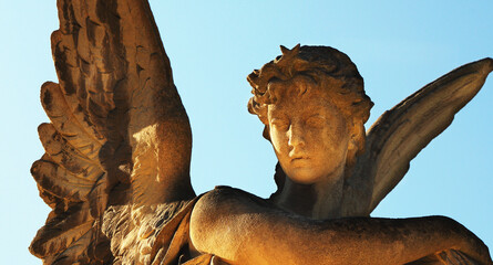 Gold angel in the sunlight. Ancient statue. Fragment. Horizontal image.