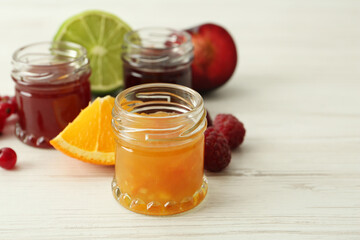 Jars of different jams and ingredients on white wooden table