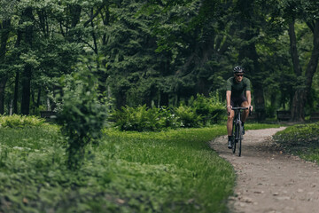 Fototapeta premium Young athlete enjoying morning cycling at summer park