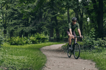 Fototapeta na wymiar Caucasian man in sport clothes riding bike at park