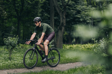 Strong man in protective helmet and glasses cycling outdoors