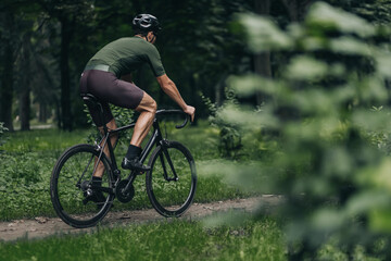 Fototapeta na wymiar Muscular man using black bike for cycling on trail road