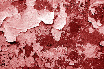 Сement wall with peeling paint and plaster in red tone.