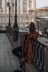Stylish young brunette woman in fashionable long brown leather coat. Autumn street style. Casual fashion. Copy, empty space for text