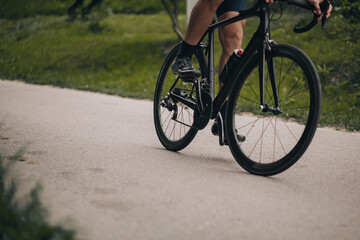 Close up of man muscular legs riding bike at green park