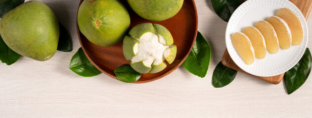 Fresh pomelo fruit on bright wooden table background.