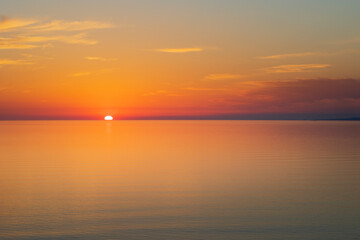 Fototapeta na wymiar Sun going down at sunset over a calm sea