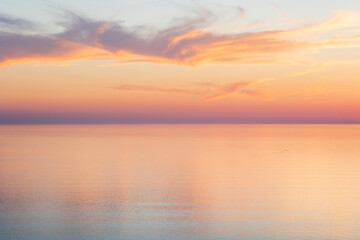 Fototapeta na wymiar Whispy clouds at sunset over a calm sea