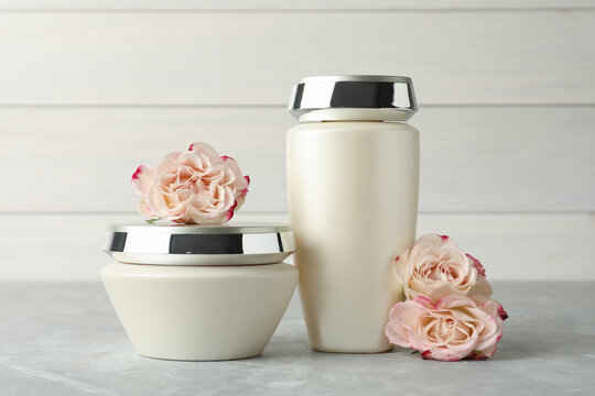 Hair care cosmetic products and beautiful flowers on light grey marble table