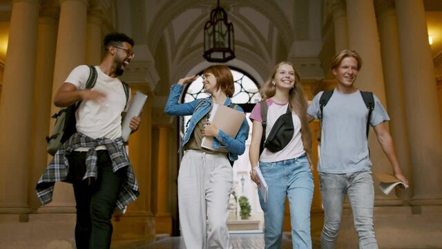 Group of happy students walking through university building.