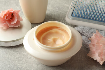 Obraz na płótnie Canvas Jar of hair care cosmetic product and flowers on light grey table, closeup