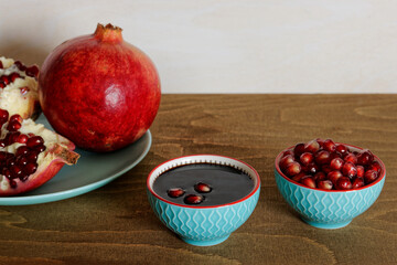 Pomegranate molasses in small bowl. Pomegranate sweet and sour syrup with pomegranate fruit and seeds.