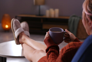 Fototapeta na wymiar Woman with cup of aromatic coffee relaxing at home, closeup. Space for text