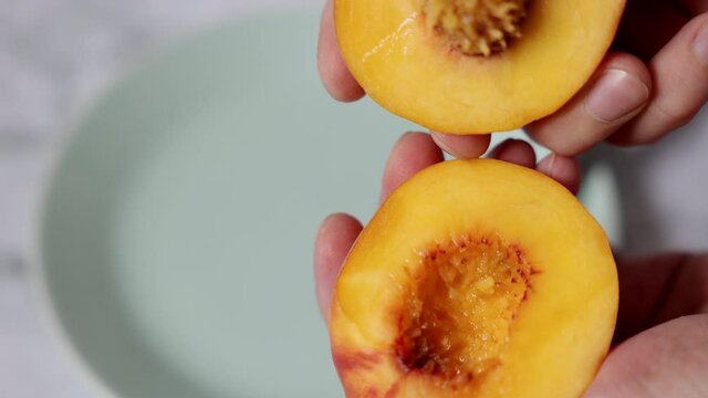 The process of both slicing the peach and dividing it into two halves. Juicy and ripe fresh fruits