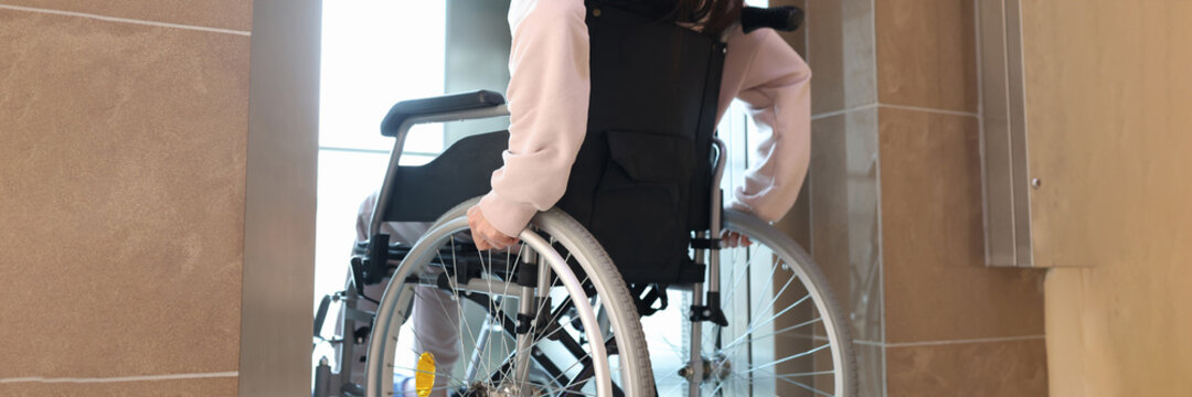 Disabled Woman In Wheelchair Entering Elevator Back View