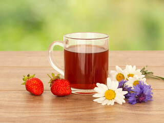 Glass cup of tea with white chamomile flowers