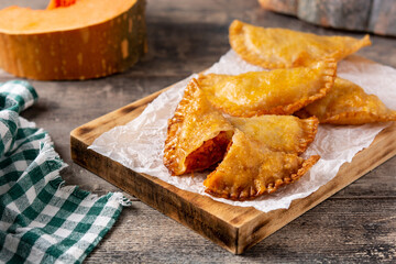 Pumpkin empanadillas on wooden table.	