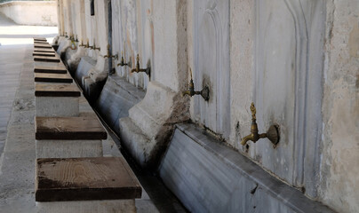 Ablution or wudhu station at mosque in Istanbul, Turkey. Faucets for ritual ablution and stones to sit on near a mosque in Islamic culture. Turkish Ottoman style water tap.