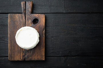 Whole fresh ricotta cheese, on wooden board, on black wooden table background, top view flat lay , with copyspace  and space for text