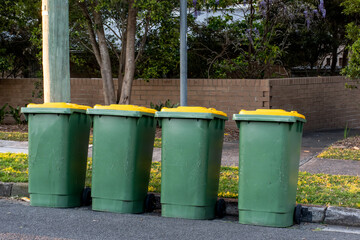 Australian garbage wheelie bins with colourful lids for recycling household waste on the street kerbside for council rubbish collection. - obrazy, fototapety, plakaty