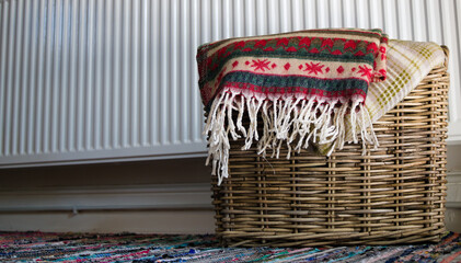 Warm blankets in wicker basket in front of the radiator