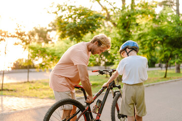 Obraz premium Ginger white man teaching his son how to ride bicycle in park