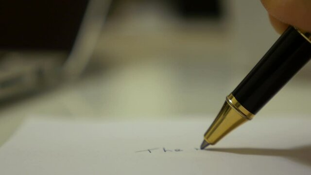 ball pen writing on a paper by a man macro shot