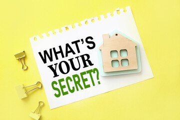 Whats Your Secret? notepad with place for text on a yellow background. near a wooden house. home buying concept. housing rent