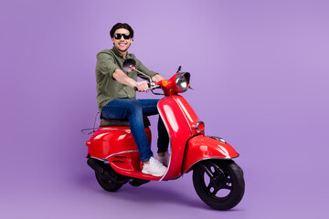 Fototapeta na wymiar Full body photo of positive happy cheerful man wear sunglass ride motorbike isolated on violet color background