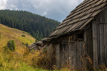 Abandoned buildings in the mountains, wooden houses against the background of rocks, the natural landscape, green meadows and forests