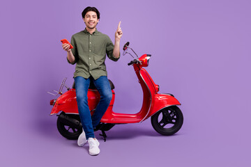 Fototapeta na wymiar Full size photo of positive happy young man idea biker hold hand phone isolated on purple color background