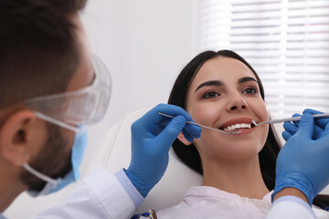 Dentist examining young woman's teeth in modern clinic