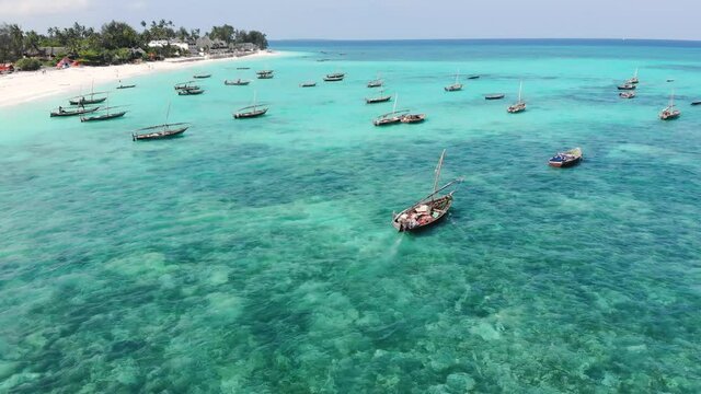 aerial drone shot on traditional unguja dhow boats near the beautiful tropical coast line at zanzibar nungwi beach in a day time with blue turquoise indian ocean