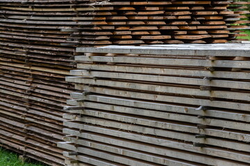 Piles of wooden boards in the sawmill, planking. Warehouse for sawing boards on a sawmill outdoors. Wood timber stack of wooden blanks construction material. Industry