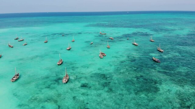 aerial drone shot on traditional unguja dhow boats near the beautiful tropical coast line at zanzibar nungwi beach in a day time with blue turquoise indian ocean