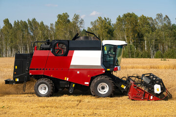 The red and white harvester is harvesting yellow wheat.