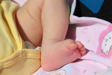Obraz na płótnie Canvas foot of a newborn baby is sunbathing. Health, treatment, dermatology, childhood, summer, rest, tours. Baby foot. The newborn sleeps outdoors in a warm, bright climate.