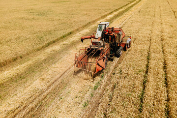 aerial view of a old Combine harvester goes on way to harvest wheat. Harvester harvests wheat in...