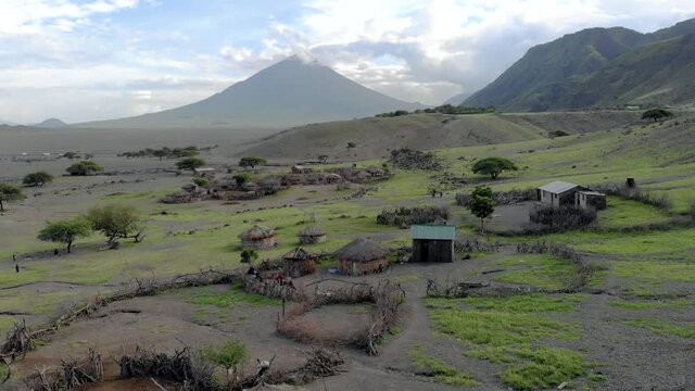 aerial flyby view on the maasai village in front of the ol doinyo lengai mountain of god in the maasai language engare sero village in arusha region i the northern tanzania africa at sunset time