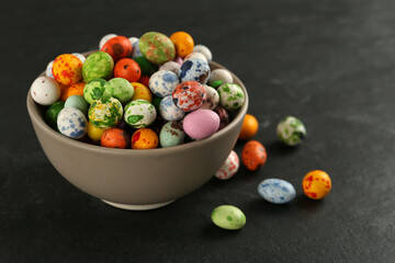 Ceramic bowl with delicious candies on dark grey table, closeup. Cooking utensil