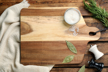 Cutting board and condiments on wooden table, flat lay. Cooking utensil